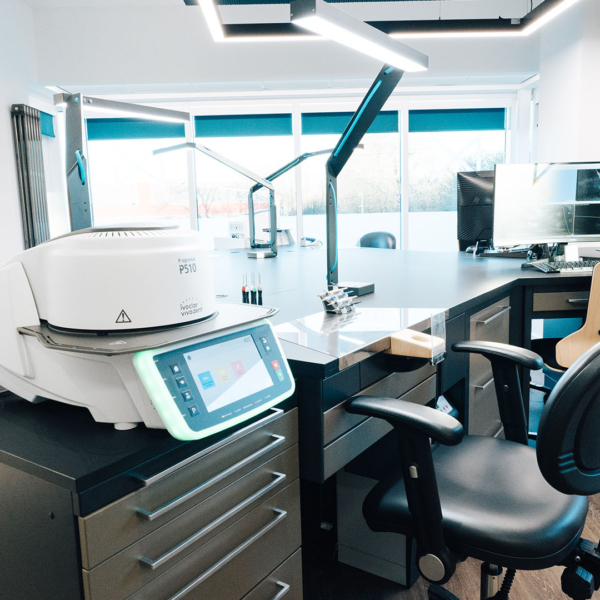 A large dark desk with multiple workspaces, with computer spaces and glass work tops in a high-tech lab.